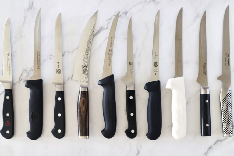 A professional boning knife on a wooden board next to fresh raw meat.