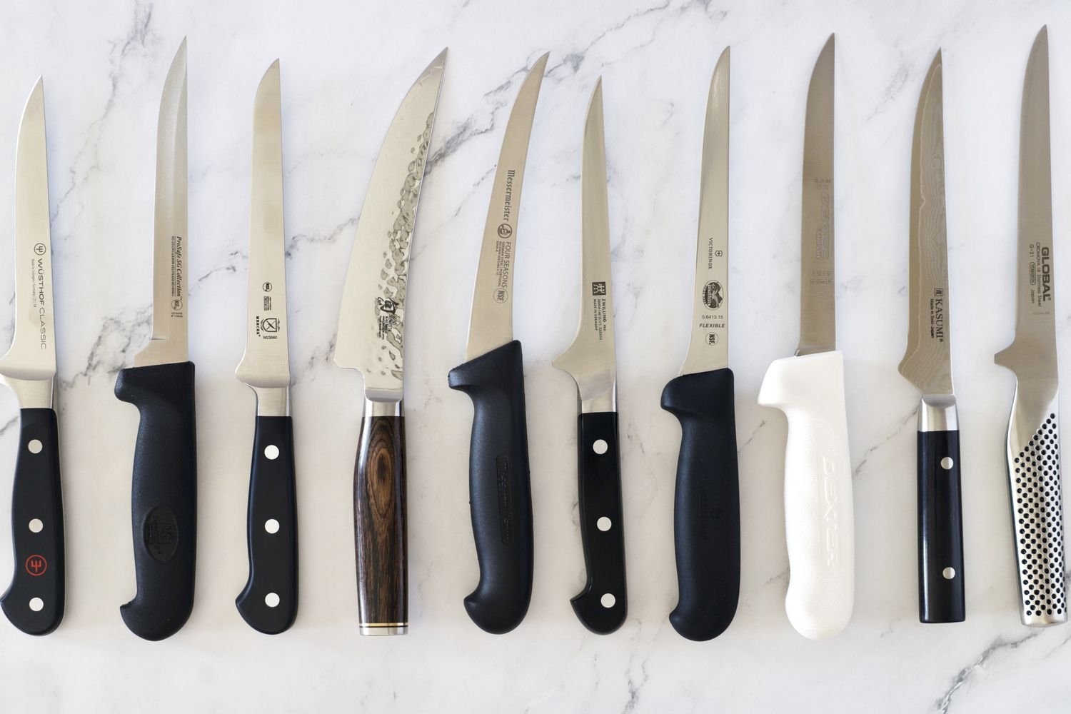 A professional boning knife on a wooden board next to fresh raw meat.