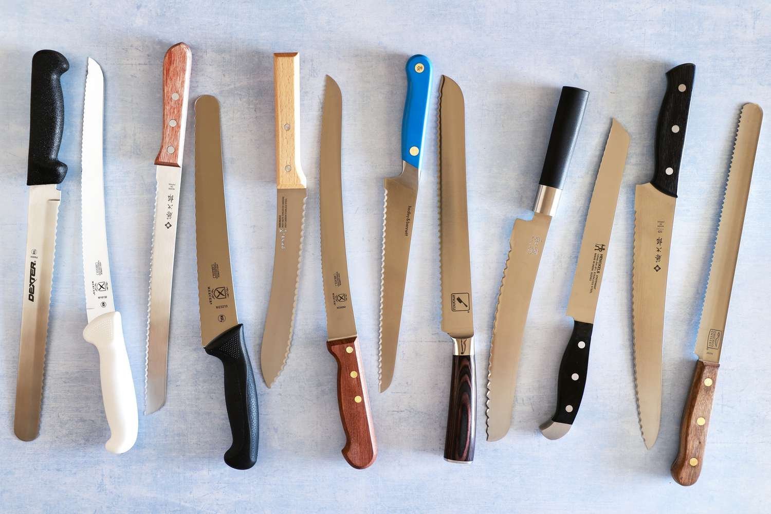 A sharp bread knife sitting beside a loaf of sourdough on a wooden board.