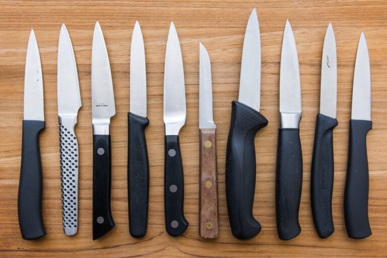 A sharp paring knife sits on a wooden board next to fresh ingredients.