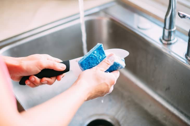 Essential cleaning supplies for washing kitchen knives arranged on a wooden board.