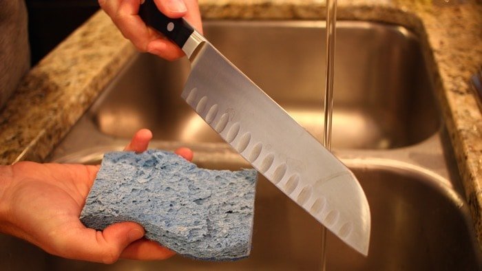A kitchen knife on a cutting board waiting for immediate cleaning after use.
