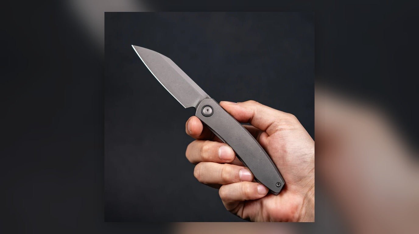 Close up of a kitchen knife blade edge resting on a glass cutting board.